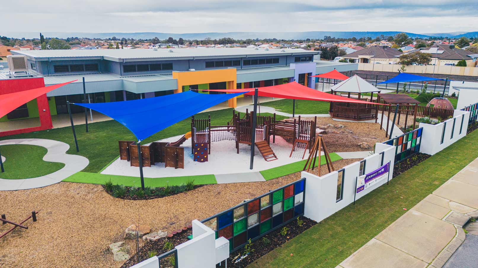 Childcare playground in Perth with timber play equipment, shade sails and artificial grass