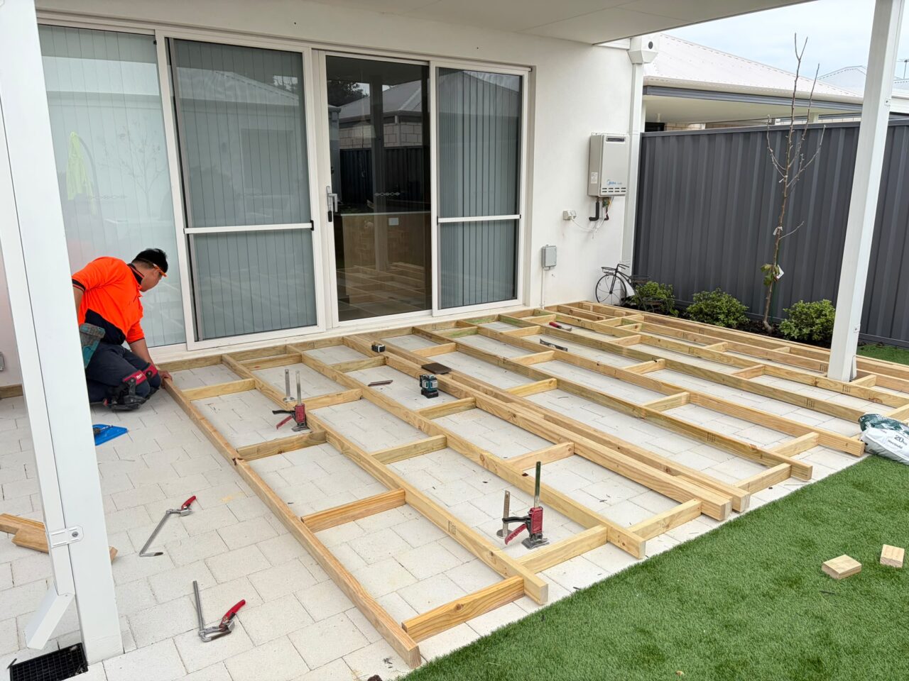 Composite decking subframe set out over pavers beside an artificial lawn, Perth